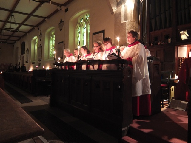 A photograph of a robed choir singing by candlelight