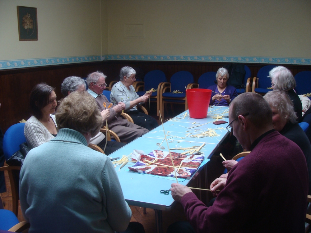 People seated around a table making palm crosses