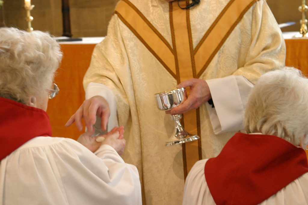 An image of a Priest distributing Communion to a chorister at St Michael's