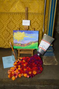 A flower arrangement in St Michael's Church, showing a canvas and flowers spilling out from a tube of paint