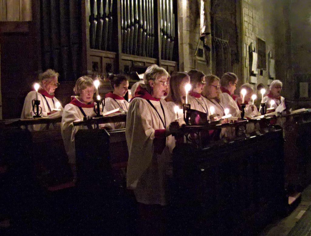 A photograph of white-robed choristers holding candles and singing
