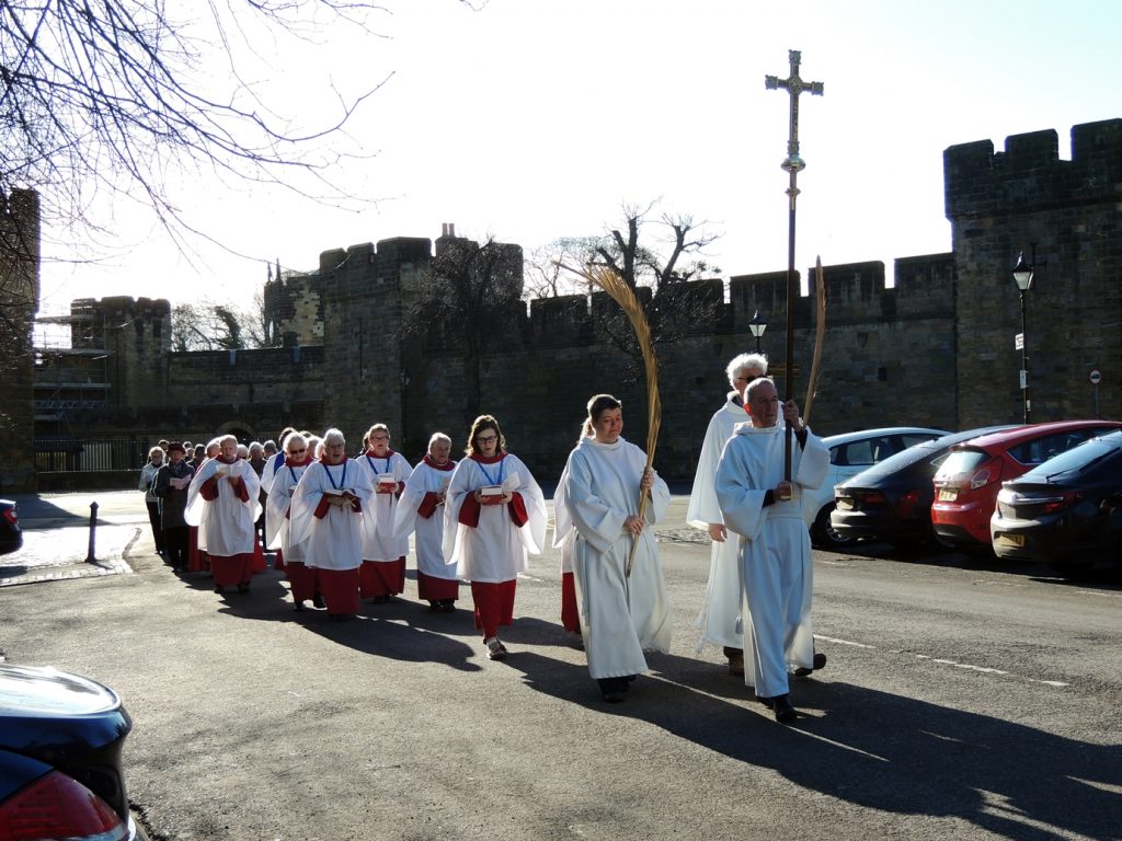 A procession of servers and choristers bearing palms