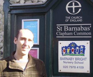 A photograph of Rev'd Gerard Rundell standing outside St Barnabas', Clapham, where he was parish assistant