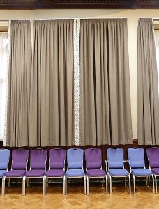 A photograph of curtains and purple chairs in St Michael's Parish Hall